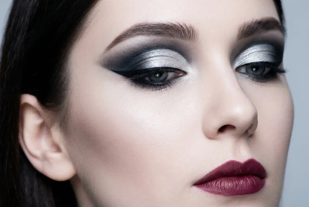 Jak dobrać cienie do powiek? Zobacz, jak dobrać cienie pod kolor oczu i jak pracować cieniami, by powieka zachwycała! Zbliżenie na modelkę o zimowym typie urody, prezentującą mocny i wyrazisty makijaż oczu oparty na krystalicznej wyrazistości i kontrastach chłodnych cieni, takich jak grafit i lodowe srebro, podkreślający jej elegancję.